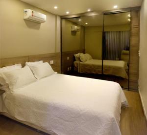 a bedroom with a large white bed and a mirror at Belíssimo Apartamento Centro de Itaipava All Suites in Itaipava +20 photos