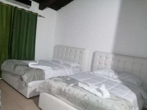 2 białe łóżka w pokoju z zielonymi zasłonami w obiekcie Casona del Valle w mieście Potrerillos