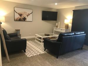 una sala de estar con 2 sillas y una vaca en la pared en Inn Scone, en Scone