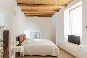 a white bedroom with a bed and a flat screen tv at La Posteria by iCasamia in Orino