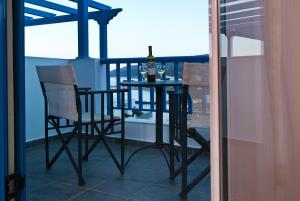 a table and chairs on a balcony with a bottle of wine at Romantica Hotel in Agia Pelagia