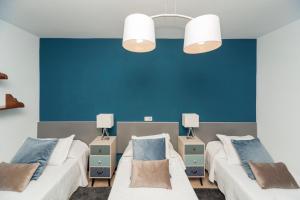 two beds in a room with blue walls at Luxury House Grumete in Playa Honda