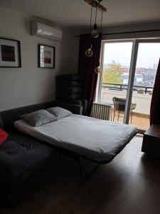 a bedroom with a bed and a couch and a window at TiTo LuX in Belgrade