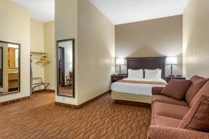 a hotel room with a bed and a couch and a mirror at Comfort Inn at Thousand Hills in Branson