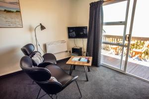 カカ・ポイントにあるNugget View Kaka Point Motelsのリビングルーム(椅子、テーブル付)、バルコニーが備わります。