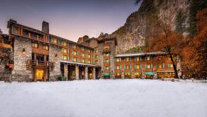 a large building with snow in front of a mountain at The Ahwahnee in Yosemite Village