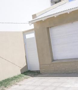 een witte garagedeur aan de zijkant van een huis bij Casa en Claromecó La Alegria in Balneario Claromecó