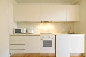 a white kitchen with white cabinets and a microwave at FLH Aliados Loft in Porto