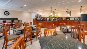 un restaurante con mesas y sillas y una cocina en Best Western Pineywoods Inn en Atlanta