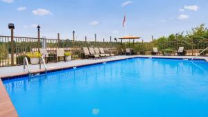 una gran piscina azul con sillas y sombrilla en Best Western Pineywoods Inn en Atlanta