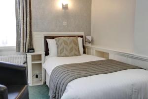 a bedroom with a bed with a chair and a window at Best Western Royal Hotel in Saint Helier Jersey