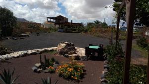 a garden with flowers and a building in the background at Casa Rural SoleaRio in La Oliva