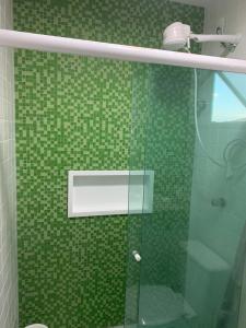 a green tiled bathroom with a glass shower door at Lindo Vilage Reserva Imbassaí in Imbassai