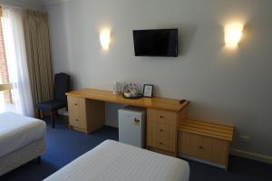 a hotel room with a desk and a tv on the wall at Elkanah Lodge and Conference Centre in Marysville