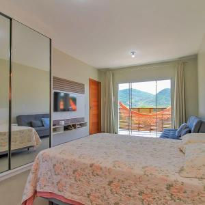 a bedroom with a large bed and a balcony at Dunas Studios in Garopaba