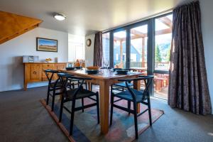 a dining room table with chairs and a large window at *** LAKE VILLA 466 *** in Hanmer Springs