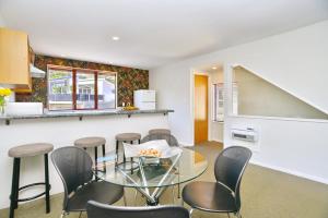 Un comedor con una mesa de cristal y sillas. en Central Akaroa Retreat - Balcony and Parking -Tumeke Akaroa, en Akaroa
