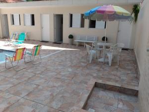 a patio with a table and chairs and an umbrella at Pousada Sanlubia Enseada Guarujá in Guarujá