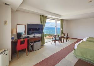 a hotel room with a bed and a desk with a television at Hotel Yugaf Inn Okinawa in Nago