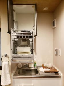 eine Küche mit einer Spüle und einer Mikrowelle in der Unterkunft Machiya Kaemon in Kyoto