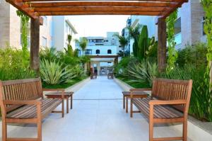 two wooden benches sitting under a wooden pergola at Enseada Arvoredos in Guarujá +13 photos