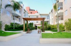 a pavilion with benches in a courtyard with buildings at Enseada Arvoredos in Guarujá