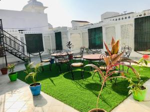 patio ze stołami i krzesłami oraz zieloną trawą w obiekcie Royal Heritage Villa Udaipur w mieście Udaipur