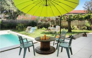 einen Tisch und Stühle mit einem Sonnenschirm neben einem Pool in der Unterkunft Beautiful Home In Nissan Lez Enserune in Nissan-lez-Enserune + 9 Fotos