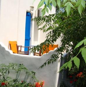 a white building with a blue window and some plants at Hotel Minoa in Katapola