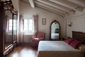 sypialnia z łóżkiem, krzesłem i lustrem w obiekcie Hotel IRARAGORRI w mieście Galdakao