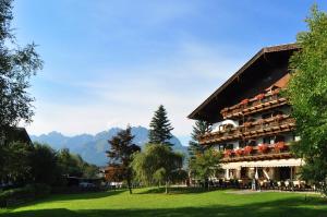 ein Hotel mit grünem Rasen und Bergen im Hintergrund in der Unterkunft Kaiserhotel Kitzbühler Alpen in Oberndorf in Tirol