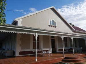 Casa con porche con mesa y sillas en Monte Rosa Guesthouse en Rawsonville