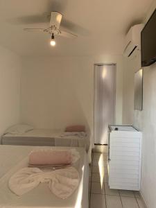 um quarto branco com 2 camas e uma televisão em Pousada Castelo do Mar em Jacaraípe