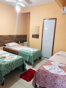 um quarto de hotel com duas camas e duas mesas em Pousada Castelo do Mar em Jacaraípe