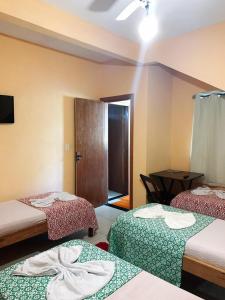 um quarto com três camas e uma mesa em Pousada Castelo do Mar em Jacaraípe