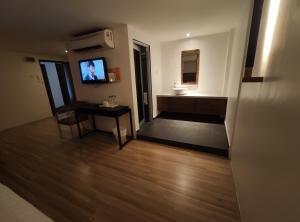 uma sala de estar com uma televisão e uma mesa com uma cadeira em T Hotel Tandop em Alor Setar