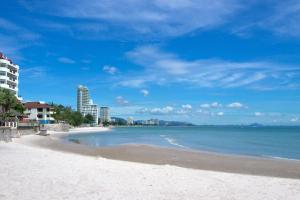 a sandy beach with buildings and the ocean at Tong Mee House Hua Hin in Hua Hin