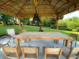 a wooden table and chairs under a gazebo at Villa Alba. Piscine grand jardin Hauts de Bordeaux in Carignan