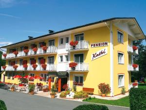 a yellow hotel with red flowers on the balconies at Pension Kathi in Sankt Kanzian