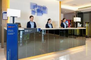 3 Personen stehen an einer Theke in einer Lobby in der Unterkunft Holiday Inn Express Taichung Park, an IHG Hotel in Taichung