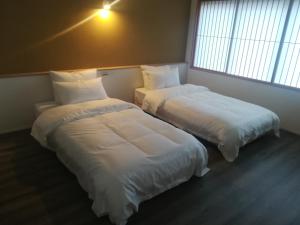 dos camas sentadas una al lado de la otra en una habitación en Hotel Shun, en Nishijin