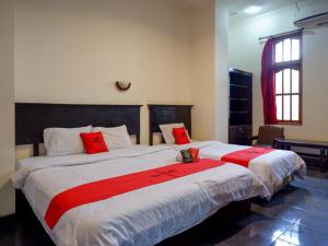 a bedroom with two beds with red pillows at RedDoorz near Tugu Yogyakarta in Yogyakarta