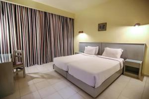 1 dormitorio con 1 cama blanca grande y 1 silla en Sunny Days Mirette Family Resort, en Hurghada