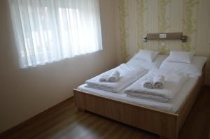 a bedroom with a bed with towels and a window at Bettina Vendégház in Kiskőrös