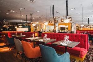 un restaurant avec un canapé rouge, des tables et des chaises dans l'établissement Hotel Rival, à Stockholm