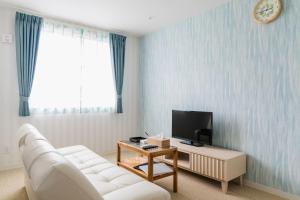 Una sala de estar con un sofá blanco y un televisor. en Ecot Irabu Bridge Sunset Hills, en Isla Miyako