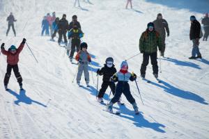 a group of people skiing down a snow covered slope at GRAND MONASTERY Apartments in Pamporovo