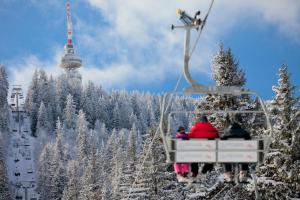 a group of people riding a ski lift in the snow at GRAND MONASTERY Apartments in Pamporovo