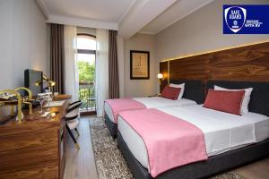 Habitación de hotel con 2 camas, escritorio y TV. en Tiflis Palace, en Tiflis