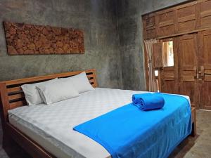 ein Bett mit einer blauen Tüte darüber. in der Unterkunft Watukarung Ristu Homestay in Kalak